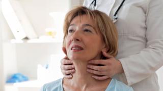 A woman having her throat examined by a doctor