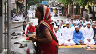 কলকাতায় রাস্তায় ঈদের নামাজ পড়ছেন মুসলিমেরা। রাস্তায় পাশেই আছে একটি মন্দির। সেখানে পুজো দিচ্ছেন এই হিন্দু মহিলা।