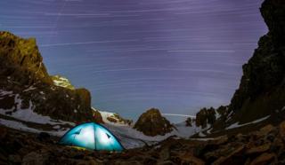 A long exposure picture shows stars and meteor trails above the mountains of Tien Shan.