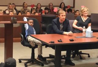 A picture shared by Kent County, Michigan's Facebook page shows a little boy named Michael being formally adopted in court, watched by his Kindergarten classmates