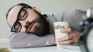 Homem deitado com copo de café ao lado