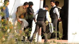 Police officers combing the site after the operation that killed the suspected militant