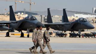 Oficiales sauditas caminan junto a cazas F-15 en una base aérea en Riad.