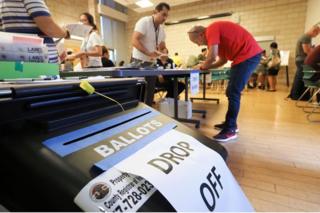 Assistentes e eleitores em sala de votação na Califórnia