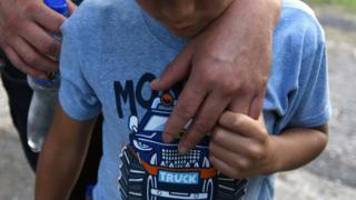Un niño toma la mano de su padre. Ambos son inmigrantes que fueron deportados de EEUU a su país de origen en julio.