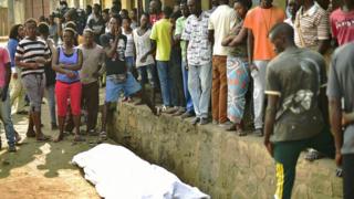 Люди собираются вокруг тела мужчины, застреленного в районе Ньякабига в Бужумбуре 21 июля 2015 года