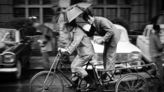 A man stands on a platform attached to a moving bicycle