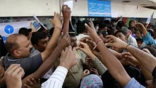 Индийцы протягивают руки, чтобы забрать у полицейского квитанции об изъятии, чтобы депонировать и обменивать снятые с производства банкноты за пределами Государственного банка Индии в Мумбаи, Индия, четверг, 10 ноября 2016 года.