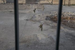 نوجوان مبارز کوبانی در حال ورود به ساختمان مدرسه، خود را از تیررس تک تیراندازهای داعشی دور نگه می دارند.