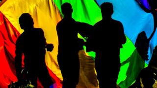 Revellers partying behind a gay pride flag