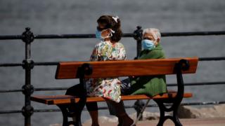 Two women sitting on a bench by the sea in Brighton.