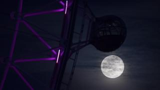 Der Super Pink Moon erhebt sich neben dem London Eye in London, Großbritannien, am 7. April März 2020