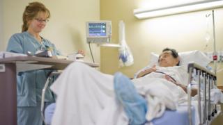 A medical professional stands near a patient.
