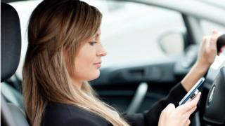 Женщина пользуется мобильным телефоном в машине