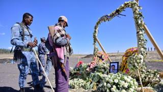 Personas ante un homenaje con flores a las víctimas