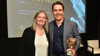 Amy Hennig and Nolan North pose with his BAFTA