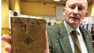 David Keys holds A Simple Prayer Book for Soldiers issued by the Catholic Truth Society which belonged to Private James Monaghan that has a hole made by the bullet that killed him