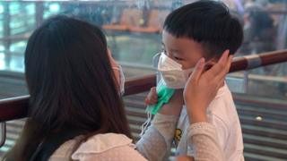 Une femme portant un masque aide son fils à mettre son masque à l'aéroport de Changi le 25 janvier 2020 à Singapour.