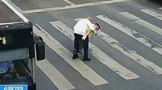Полицајац помаже старијем човеку да пређе улицу