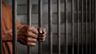 Brazos de un hombre tras las rejas