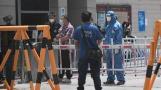 Guardias de seguridad en un área residencial bajo restricciones cerca del mercado oriental de Yuquan en Beijing