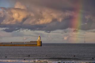 Rainbow over surfers at sea