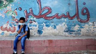 A Palestinian student, wearing a protective face mask, sits in the courtyard on the first day of school in the village of Salem east of Nablus in the West Bank on 6 September 2020.