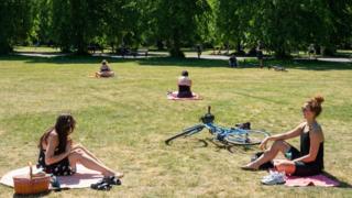 Two women observe social distancing whilst enjoying the hot weather in Greenwich Park, London, 20 May, 2020