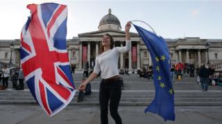 Протестующий против Европейского Союза держит флаги Союза и Европы на Трафальгарской площади