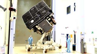 Cientistas com máscaras e jalecos olham para o Solar Orbiter dentro de laboratório