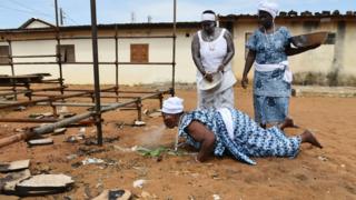 A priestess lies on the floor and spits water on two eggs.