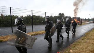 Police in riot gear protected contractors as they tried to remove bonfire material