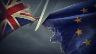 Ножницы режут ткань, показывая Юнион Джек и флаг ЕС