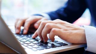 Man typing on lap top computer