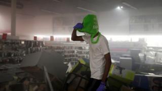 A man covers his head with a shopping bag inside a damaged office supplies store in Minneapolis