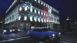 La Manzana de Gómez desde fuera y de noche, rodeada de autos clásicos en el centro de La Habana