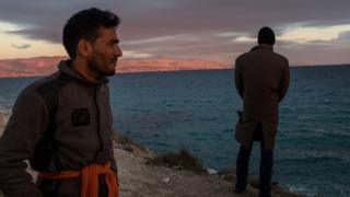 Afghan migrants look at Chios from Cesme beach near Izmir