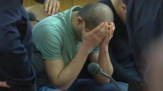 A defendant covers his face at the beginning of his trial on gang-raping a German tourist in Vienna, Austria