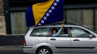 A man waves the Bosnian flag in Sarajevo on October 6, 2018