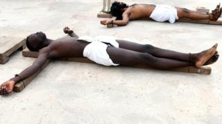 Two men lying on the floor, demonstrating crucifixion