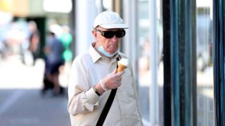Man pausing outside to eat an ice-cream.