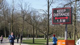 environment People running pass a sign urging people to practice social distancing in Amsterdam