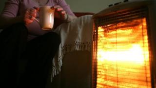 Pensioner in front of heater