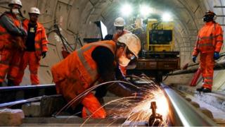 Construction workers work on a section of train track inside a Crossrail tunnel, beneath Stepney in east London in 2016