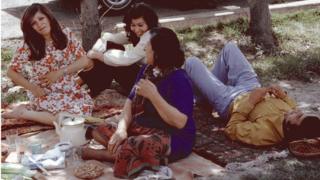 A group of men and women sit having a picnic in Tehran in 1976
