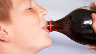 A young boy drinks cola