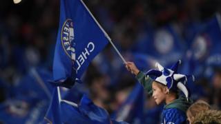 Young Chelsea supporter holds club flag