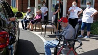 Staff watch as a visitor uses their phone to take a photo of their grandfather during a car visit to Gracewell, a nursing home in Adderbury near Banbury, west London, on May 28.