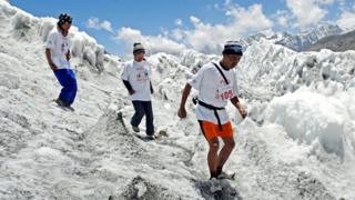 Three-people-tread-carefully-across-packed-snow-up-Mount-Everest.