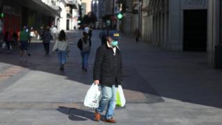 Man with bags in empty Madrid street